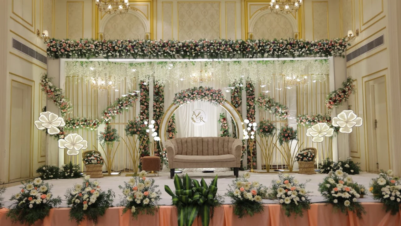 Ivory wedding stage with pink and white flowers and a beige loveseat
