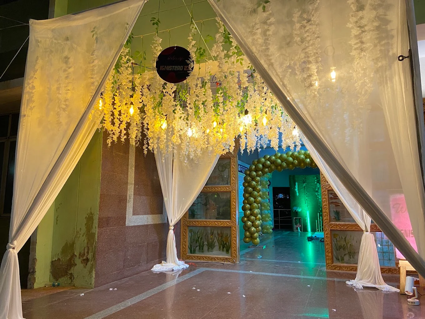 White draped entrance with hanging flowers and warm pendant lights