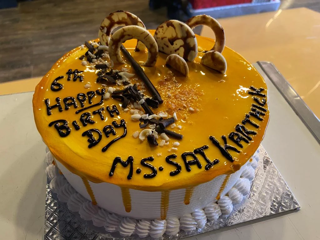 Yellow glazed birthday cake with chocolate decorations