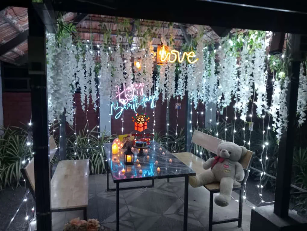 Intimate birthday dinner setup with hanging white flowers and a teddy bear