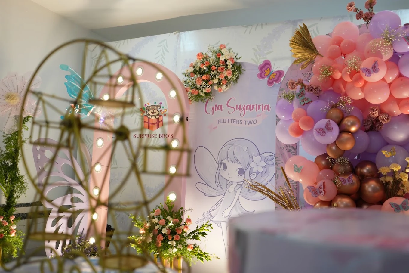Pink butterfly birthday backdrop with flowers and a gold display wheel