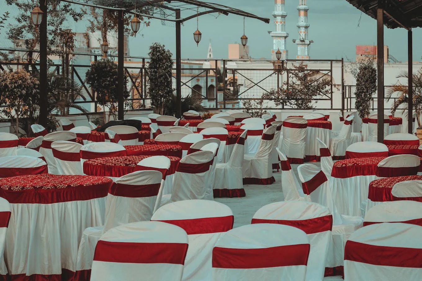 Rooftop event seating with white chair covers and red table linens